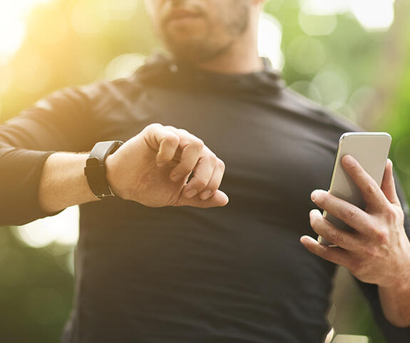 Sportler schaut auf seinen Fitnesstracker am Handgelennk