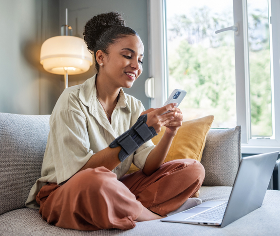 Junge mit Bandage und dem Smartphone auf dem Sofa